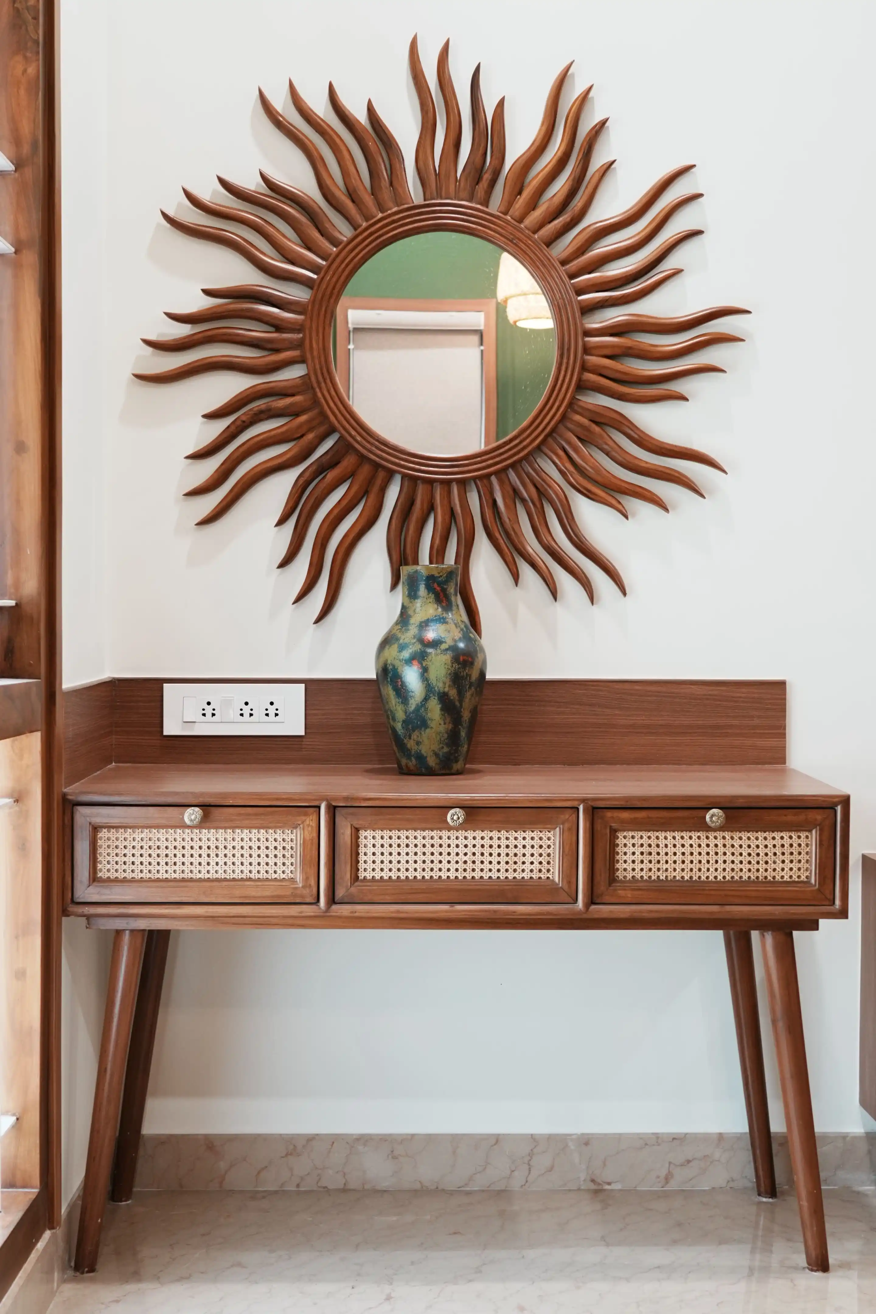 Sunburst mirror above a cane console table